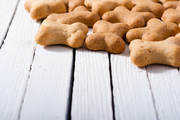 bone shape dog biscuits on white wood background