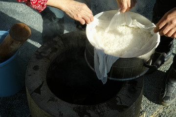 An elderly couple looking at the mochigome (rice used to make mochi) before putting it the large mortar