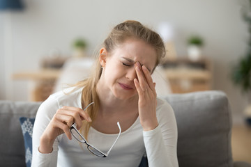 Tired teen girl rubbing eyes feeling eyestrain taking off glasses