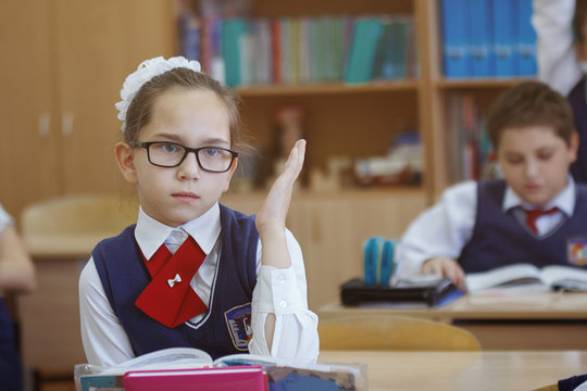 Schoolboy and his classmates sitting by individual desks and carrying out exam assignments at lesson