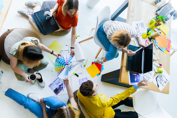 Top view of creative workers having informal meeting in office space. Architects and interior...