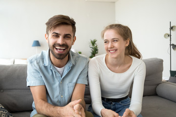 Cheerful young couple bloggers looking laughing at camera at home 