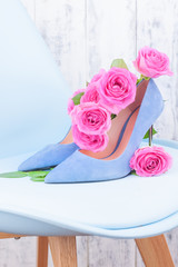 Women's shoes blue high-heeled. Elegant shoes and a bouquet of roses in the interior. A gift for a girl in the feast of women. spring shoes and flowers.