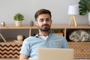 Happy relaxed young man resting with eyes closed breathing air