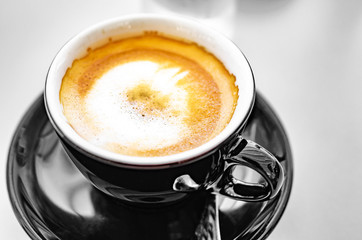 Delicious espresso coffee in a dark cup on the table.