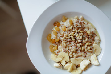 Bowl of oatmeal porridge with banana, blueberries, almonds, coconut and caramel sauce on teal rustic table, hot and healthy food for Breakfast, top view, flat lay
