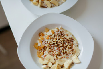 Bowl of oatmeal porridge with banana, blueberries, almonds, coconut and caramel sauce on teal rustic table, hot and healthy food for Breakfast, top view, flat lay