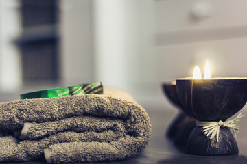 Burning spa aroma candles in coconut shell, handmade soap and towels, cozy interior background