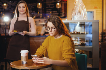 Young pretty woman and waitress in cafe.