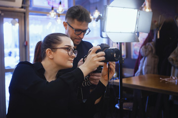 Portrait of cheerful young friends looking at smart phone while sitting in cafe. Mixed race people sitting at a table in restaurant using mobile phone.