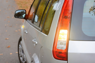 Modern grey hatchback car showing with turn signal lights beginning of moving on the road on the...