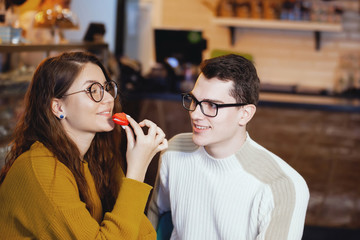 Two cute young men and a girl in a cafe.