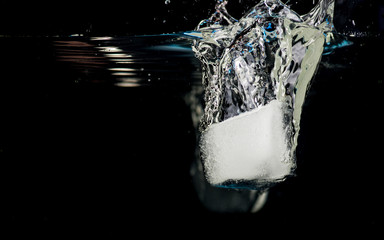 Chunks of ice thrown into water on a black background