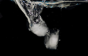 Chunks of ice thrown into water on a black background