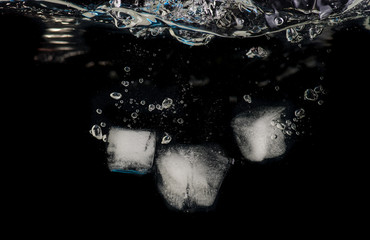 Chunks of ice thrown into water on a black background