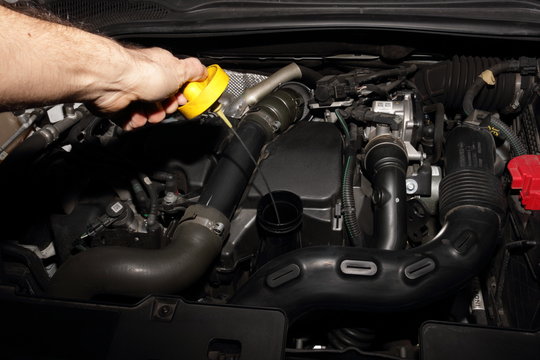 Meccanico a lavoro su di una automobile moderna per il controllo livello olio motore