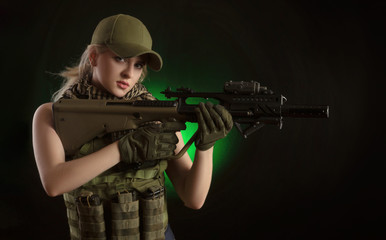 the girl in military special clothes posing with a gun in his hands on a dark background in the haze