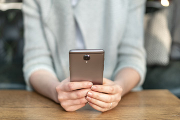 Woman holding cellular in her hands sitting behind wooden table