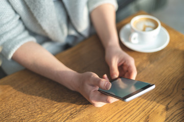 Fototapeta premium Lady holding cellular in her hands and writing message to her friends