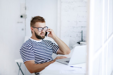 Fototapeta premium Young business man, sitting at desk at home and looking at open laptop display.
