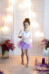 Adorable little girl dressed as a ballerina in a tutu, tying her ballet slippers. © ElenaBatkova