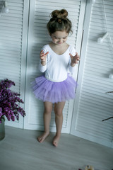 Adorable little girl dressed as a ballerina in a tutu, tying her ballet slippers. © ElenaBatkova