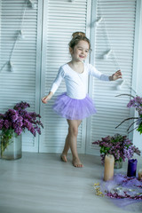 Adorable little girl dressed as a ballerina in a tutu, tying her ballet slippers. © ElenaBatkova