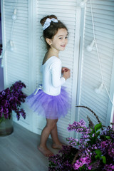 Adorable little girl dressed as a ballerina in a tutu, tying her ballet slippers. © ElenaBatkova