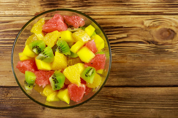 Tasty fruit salad in glass bowl on the wooden table