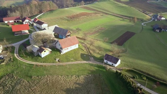 Aerial: Flying over small river with road and railway at each side. Filming beautiful green Slovenian countryside on cold sunny spring morning.