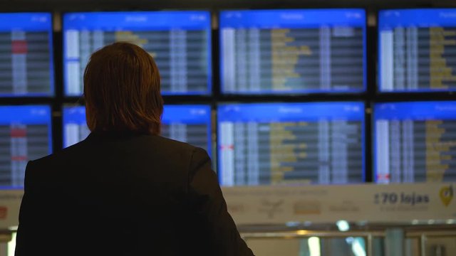 Man looking for his flight schedule on the airport panel