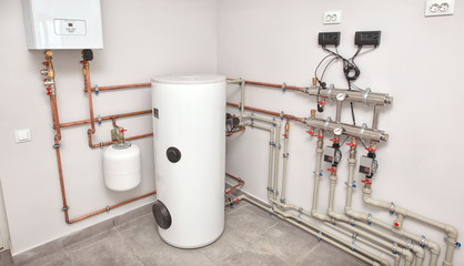 The boiler room with a lot of different equipment as a boiler, heater,pipes, expansion tank and...