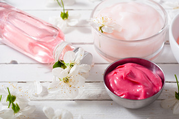 beauty products and cherry blossom on white wood table