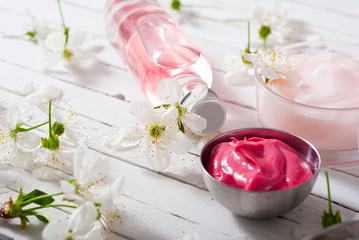 beauty products and cherry blossom on white wood table