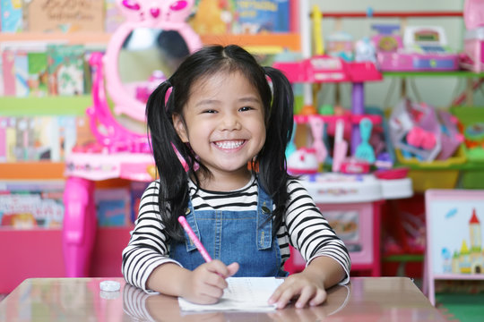Asian Child Cute Or Kid Girl Smiling Diligent Review And Enjoy Doing Mathematics Homework Or Happy Learning And Training Writing On White Paper Or Book At Nursery Preschool Or Home And Kindergarten