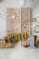 Birthday gold and silver decorations with gifts, toys, garlands and figure for little baby party on a white bricks background.