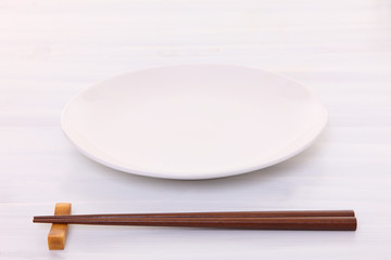 白い木製テーブルに置かれた白い皿と箸