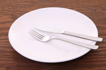 茶色い木製テーブルに置かれた白い皿とカトラリーによる食事終了の合図