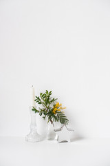 Small bouquet with green leaves and mimosa flowers and empty white wall