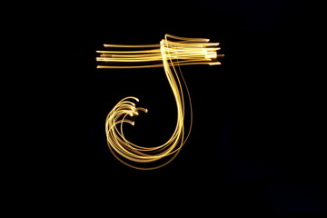 Long exposure, light painting photography.  Letter j in a vibrant neon metallic yellow gold colour against a black background.  Alphabet series.