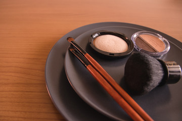 minimal concept background with make up, brushes and powders, on a grey plate, on a wooden table