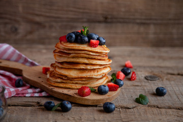 Pancakes with berries and maple syrup and sugar powder