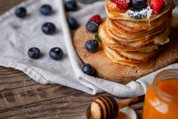 Pancakes with berries and maple syrup and sugar powder