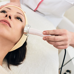 Closeup photo of professional beautician doing facial mesotherapy to young woman