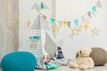 Teddy bear sits in a children's house wigwam on the background of an old wall © Angelov