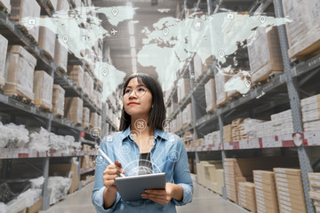 Portrait of happy young attractive asian entrepreneur woman looking at inventory in warehouse using...