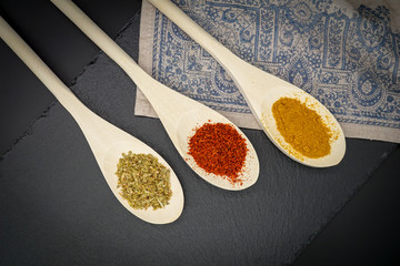 Spices in wooden spoons on dark background. Pepper chilly, basil, curry. Concept of organic food. top view.