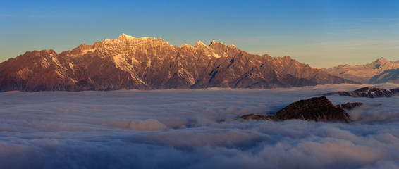 Fototapeta na wymiar Mountains floating above the sea of clouds, appearing like islands an ocean - Niubeishan Landscape, Cattle Back Mountain, Sichuan Province China. Snow mountains, fluffy clouds, panoramic scenery