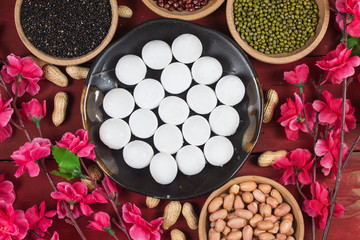 sweet dumplings in bowl on table, ang pow or red packet and gold ingots