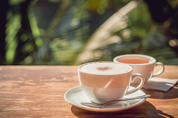 Hot coffee and hot tea place on the wooden table in early morning with copyspace, white cup and silver spoon.